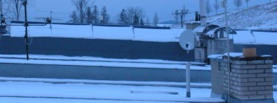 sníh na panelech na nedaleké střeše odpoledne